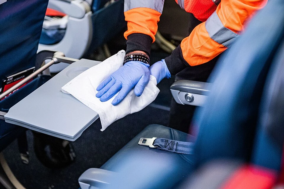 Real photograph of an airline tray table being wiped with a cloth