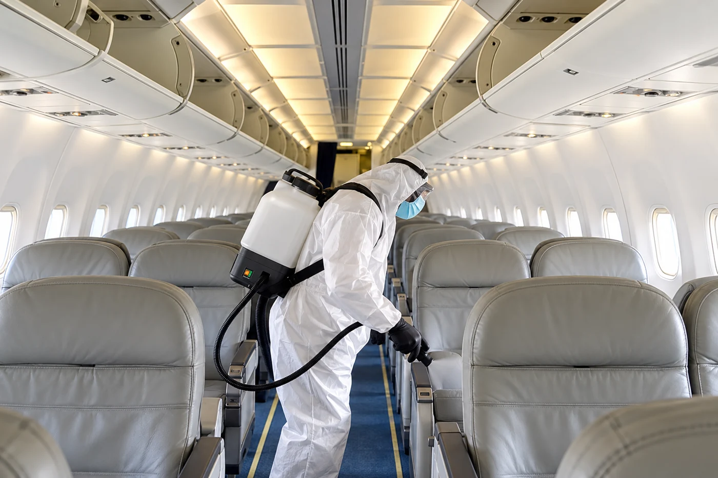 Illustrative aircraft cabin treatment scene with a protected technician and unobstructed cabin fittings